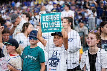 Photo of a young Mariners fan holding up a Refuse to Lose sign. 