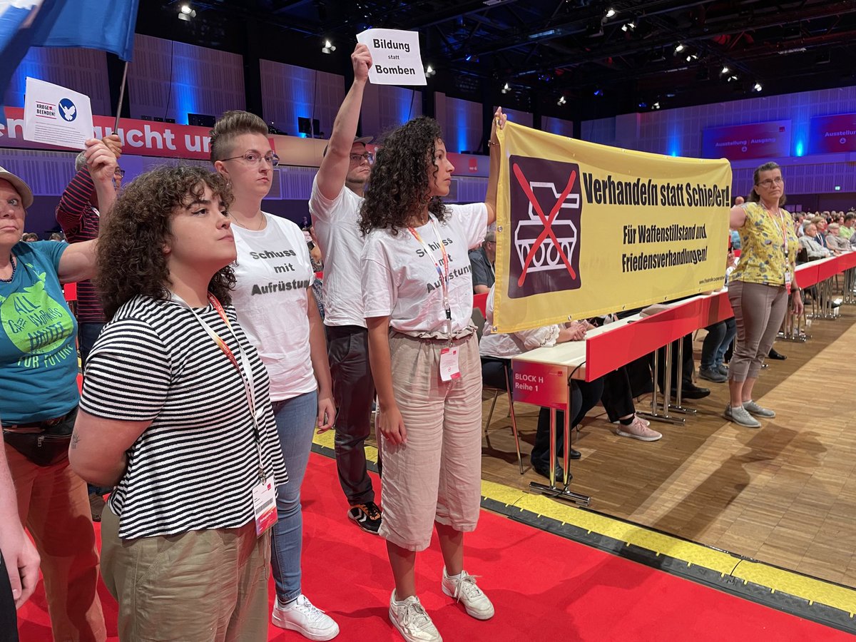 RArnsburg's tweet photo. Delegierte auf dem #6bk23 haben sich gegen die zunehmende Militarisierung während der Kanzlerrede gestellt. Sie fordern Schluss mit der Aufrüstung und 100 Mrd. Euro für Bildung, Gesundheit und Soziales! https://t.co/Zpl2qRQchl
