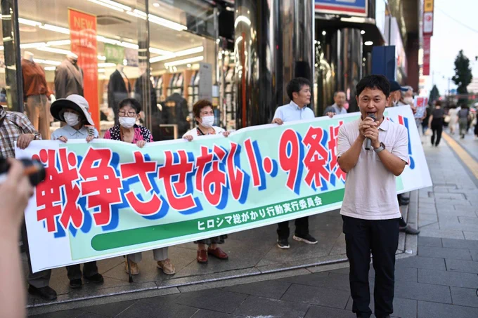 「戦争させない・９条壊すな」の横断幕の前でうったえる大平。