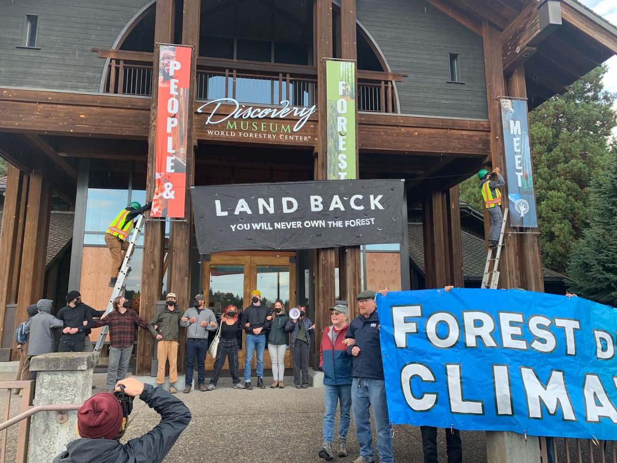 TreeSitUnion's tweet photo. BREAKING: Activists block entrance to the @World_Forestry Center in protest of the "Who Will Own the Forest?" conference as wealthy timber barons arrive for registration. 

 #landback #defendtheforest https://t.co/42VaiDKCem