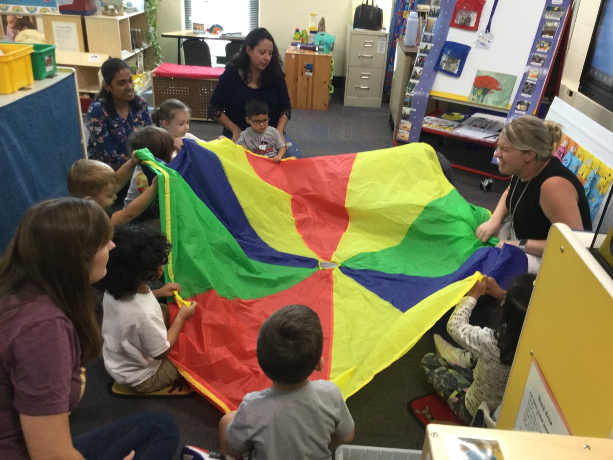 deanne_ELC's tweet photo. Ms. Megan had our AM session pretend the parachute was an umbrella to go with our book Under the Big Umbrella!  We all took turns going under!  We had fun learning our positional words! https://t.co/RjPit9PurP
