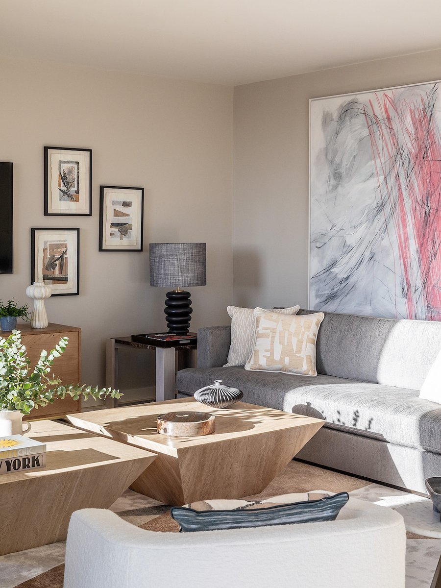 A collage of artworks created by a diverse group of artists injects colour and freeform movement in this London sitting room. Vintage travertine coffee tables sit next to a custom sofa.