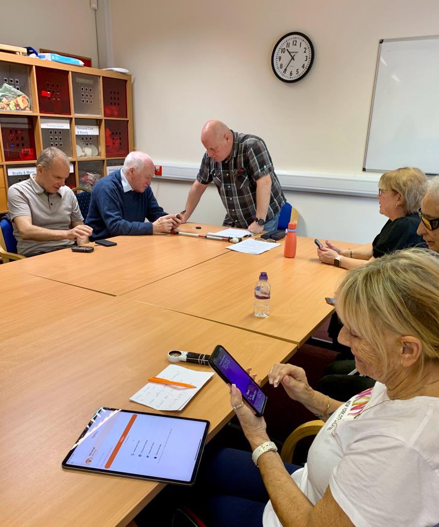 Great session today. CIKAss classroom shows a group of blind and visually impaired people sat around a large table with tablets and phones receiving instructions by a session leader.