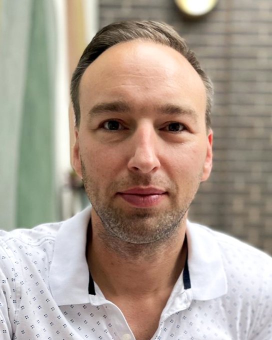 Michael Parkatti is pictured in a standard headshot in front of a brick background, wearing a white polo shirt.