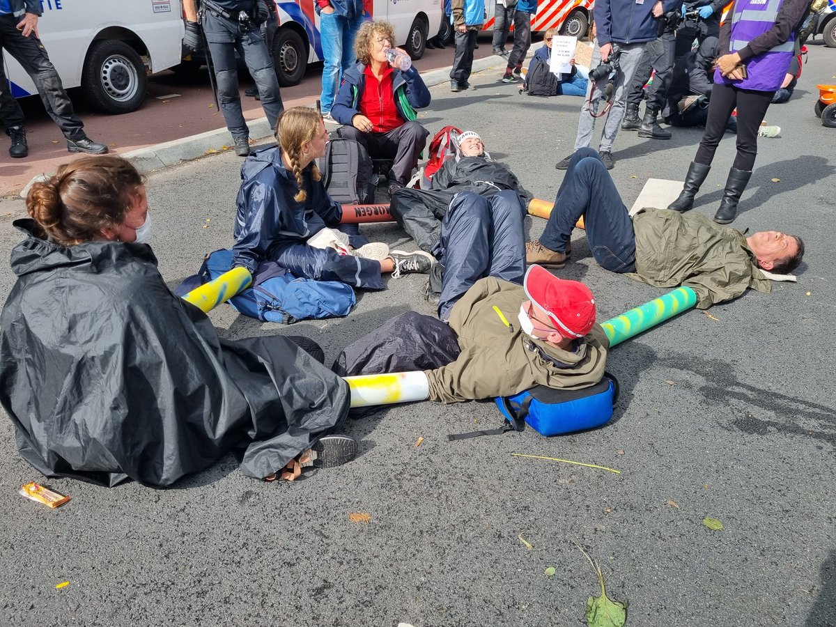 TomvndrH's tweet photo. Een aantal demonstranten zit met buizen aan elkaar vast. De politie gaat ze straks proberen los te maken. #A12 #DenHaag https://t.co/prnL8aWlqC