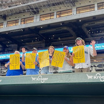 Photo of Mariners fans holding up signs with the trident on it. 