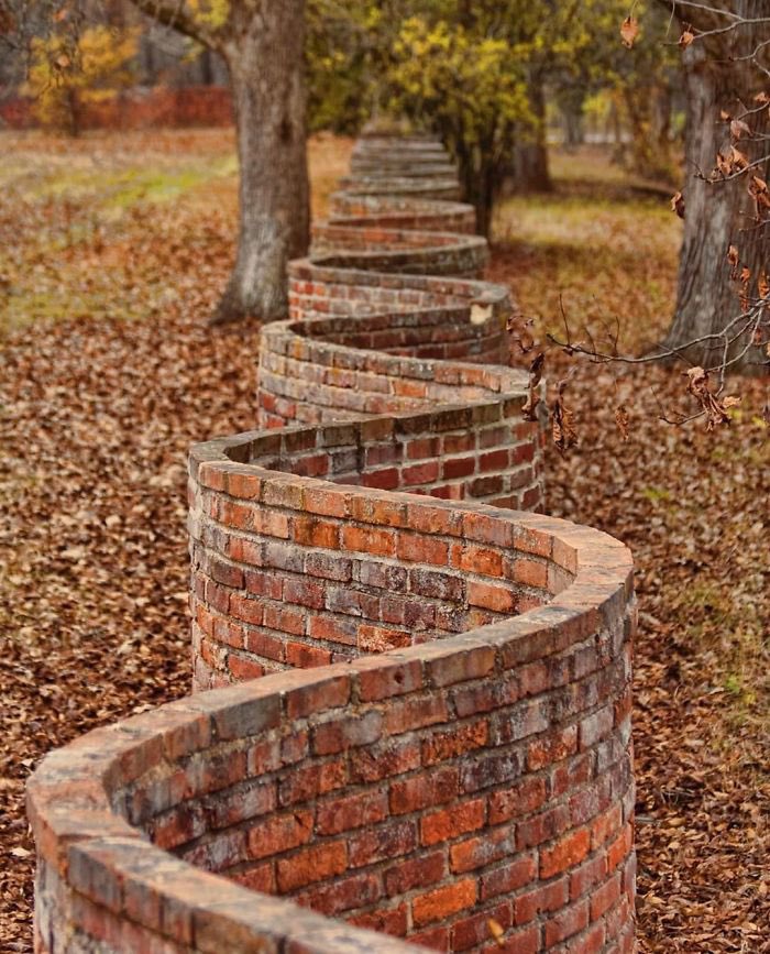 ArchitectureTud's tweet photo. In England you sometimes see these "wavy" brick fences. And curious as it may seem, this shape uses FEWER bricks than a straight wall. A straight wall needs at least two layers of bricks to make is sturdy, but the wavy wall is fine thanks to the arch support provided by the waves https://t.co/k791CgsZ2b