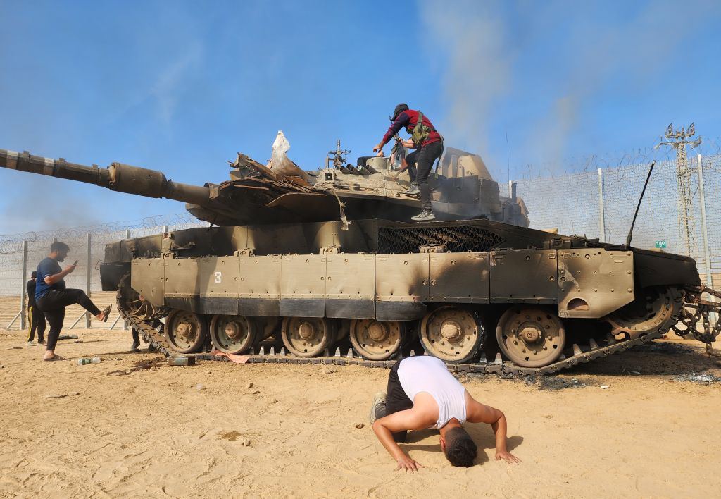 ShehabAgency's tweet photo. "كأنه يوم التحرير".. فلسطينيون يحتفلون على ركام دبابة إسرائيلية متفحمة ويعلقون أعلام فلسطين عليها في مستوطنات غلاف غزة. https://t.co/rSUAiuLxWa