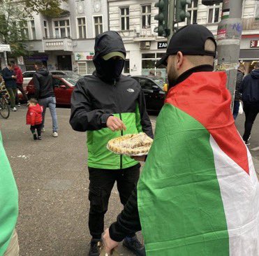 Palestinians on the streets of Berlin, celebrating the war by handing out sweets to people.