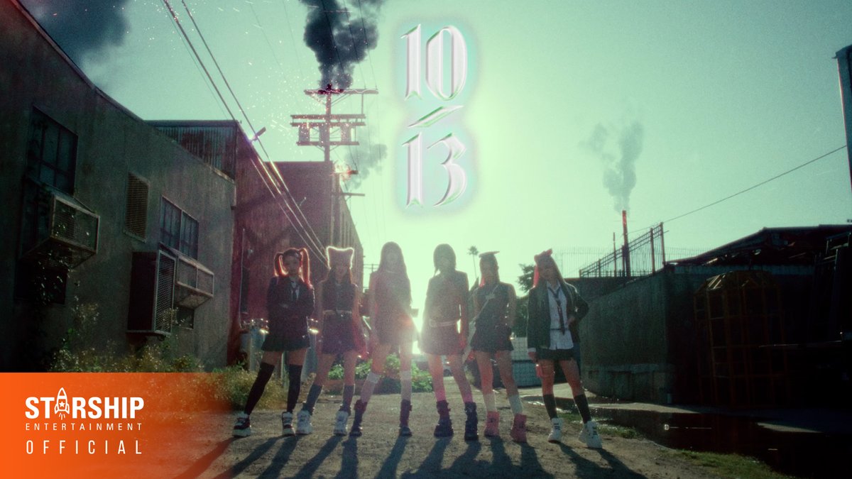 Seven young women stand confidently in an industrial alleyway with smoke rising behind them, featuring the text '10/13' and 'STARSHIP ENTERTAINMENT OFFICIAL' in the lower corner.