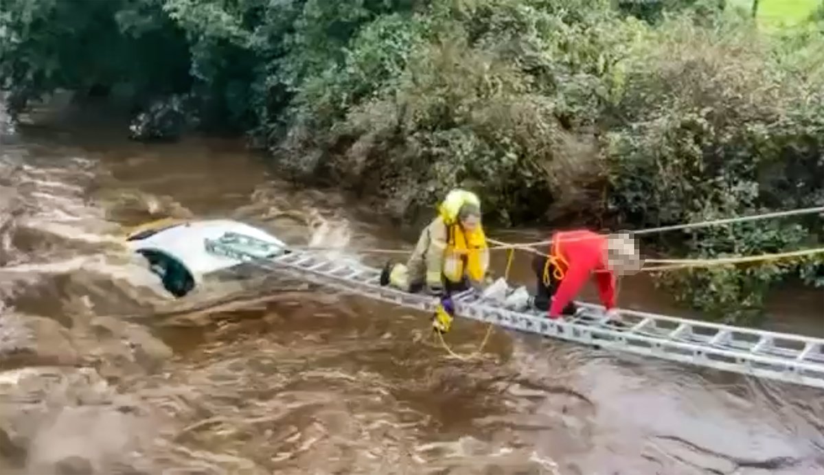 Kscott_94's tweet photo. If ever there was an image that depicted the heroism of @NIFRSOFFICIAL this would be it. 

A firefighter leads a woman to safety with just moments to spare after her car was swept away into a river earlier today in Draperstown. @BelTel 

https://t.co/NRDOFlErri https://t.co/HmCCQR1oYR