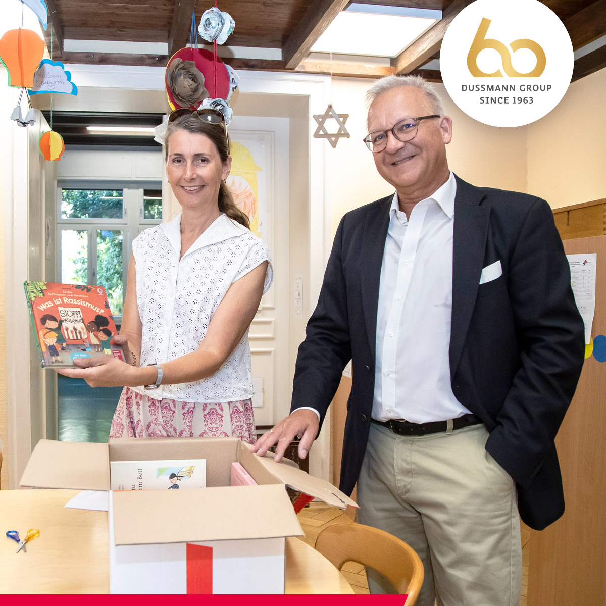 dussmann_group's tweet photo. Celebrating #60yearsofpassion with 60 book boxes for youth orgs! 📚For our anniversary, CFO Dieter Royal presented two curated book boxes to the Internationales Kinderhaus in Frankfurt. Impressed, he said: "This institution and the team support the children with heart and soul." https://t.co/rzoMr7RWKz