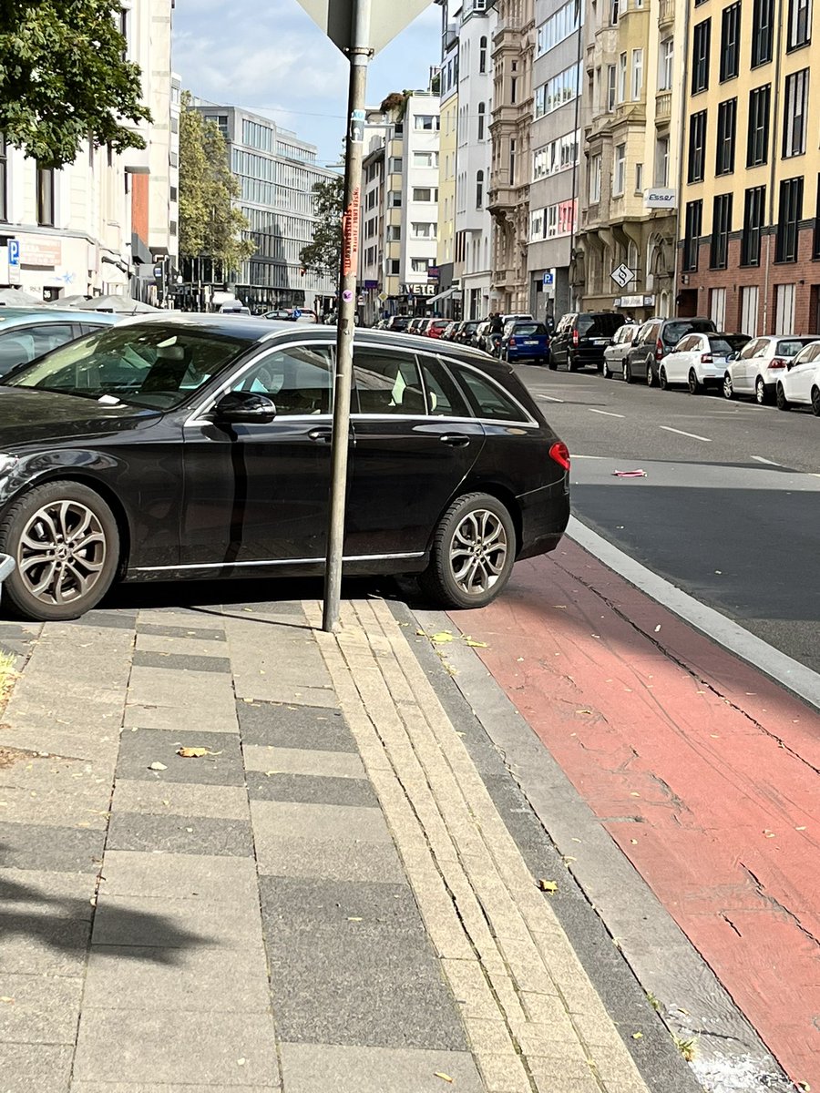 Dieses Auto blockiert den gesamten Radweg, damit ist eine akute Gefährdung gegeben. Tochter und ich mussten auf Straße in fließenden Verkehr ausweichen. Ordnungsamt war da, hat aber nur Knöllchen verteilt, statt abzuschleppen. Was ist da los <a href="/Koeln/">Stadt Köln</a>?