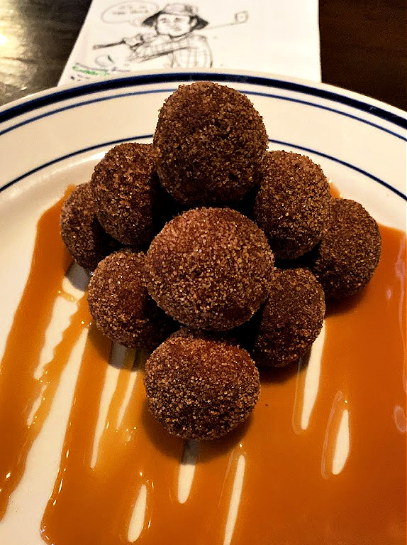 Hole-y deliciousness awaits! Dive into our Gopher Holes dessert and satisfy your sweet tooth! 🍩🍫🍊 Warm donut holes tossed in cinnamon and sugar atop a drizzle of chocolate and caramel, served with orange crème anglaise. #Caddyshack #Rosemont
