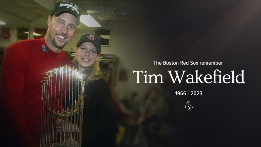 A photo of Tim and Stacy Wakefield posing with the 2004 World Series trophy in the clubhouse after winning. The graphic reads "The Boston Red Sox remember Tim Wakefield 1966-2023"