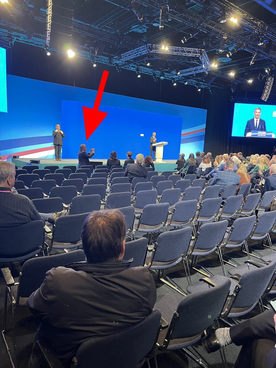 During Mark Harper's speech this morning the small amount of attendees are corralled into an area on the right so Party people like this man (red arrow) can take a deceptive photo. If anyone sees that photo on social media then do point it out #CPC23 #ConservativePartyConference