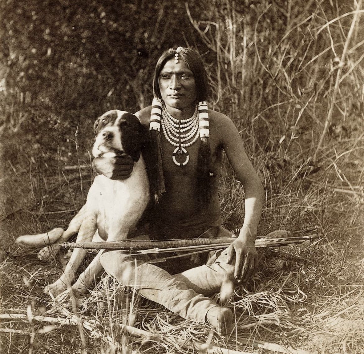 historyinmemes's tweet photo. A Ute warrior and his dog in the Eastern slope of the Wasatch Mountains, Utah, 1873.

The Ute tribe lived in present-day Utah and Colorado, mainly as a hunter-gatherer society for many centuries. They made their first contact with Europeans during the early 17th century when Spanish conquistadors arrived in the region.

The Ute tribe began trading with the Spanish in the 1670s and were known for their prized deerskin. Towards the late 17th century, the Utes had acquired horses from the Spaniards, allowing them to be more mobile, covering more ground, hunting larger game, and expanding trade. Horse ownership and warrior skills became highly valued as a status symbol among the tribe.

Mormon settlers began arriving in the region during the mid-1800s, increasing tension. The situation was further exacerbated by the gold rush, which began in the summer of 1858. Prospectors and settlers began moving into the area, and as a result, most of the Ute people were forced off their lands and moved onto reservations. The name Utah is said to have been derived from the name of the Ute tribe, which translates to "people of the mountains."

Today, most people from the Ute tribe live on reservations located in Utah and Colorado. All the Ute reservations are involved in oil and gas businesses, and some even generate revenue from casinos. Nevertheless, the annual household income of the Ute people is below that of non-native people living in the same region. Unemployment is also fairly high on the reservations as well.