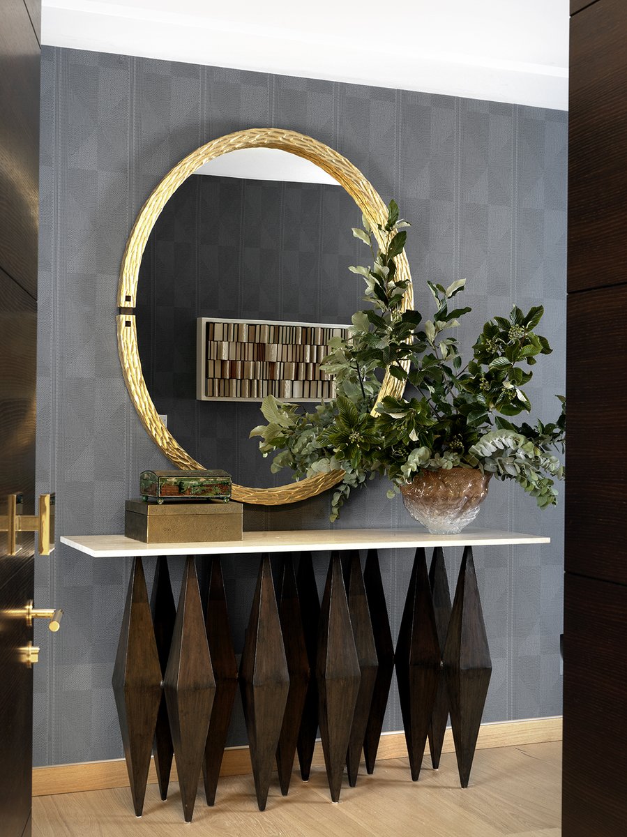 The narrow entrance hall of this London apartment has a moody palette to magnify the experience of entering the spacious, light-filled dining-living room to come. The smoky blue wallpaper is Pierre Frey.