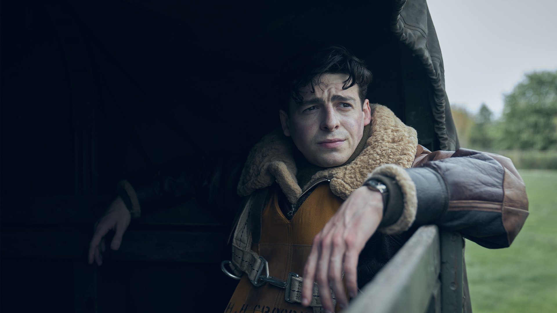 Anthony Boyle as Harry Crosby riding in the back of a Jimmy truck.