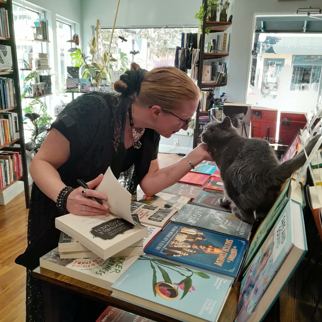 Dear Internet, please appreciate how helpful Penny the shop cat of <a href="/heartleafbooks/">Heartleaf Books</a> is, fully inspecting A HAUNTED HISTORY OF INVISIBLE WOMEN: TRUE STORIES OF AMERICA'S GHOSTS as I signed stock at this wonderful store! Penny has her own sticker! please support this GREAT shop!
