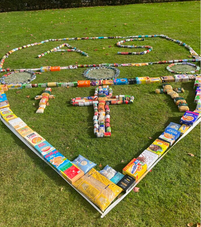 AshfordSchool's tweet photo. Our Harvest donations showcased as an Ashford School crest! Congrats to Y12 students Chloe &amp; Izzy, who as part of their @DofE Gold Award helped manage the appeal. These donations will provide vital support to those in our community who struggle to afford food. @FareShareKent https://t.co/X2X4He2MGk