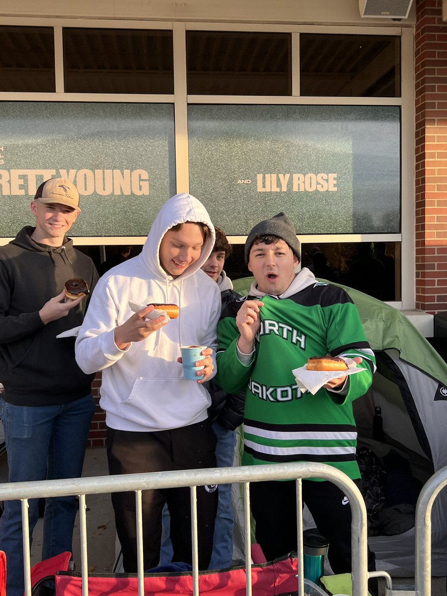 TheREA's tweet photo. The tradition continues. Students waiting in line this morning for tonight’s North Dakota/Minnesota game were treated to coffee and donuts from @HugosMarket. They even brought #greenout donuts! Thanks Hugo’s! https://t.co/SA5O9neFTm