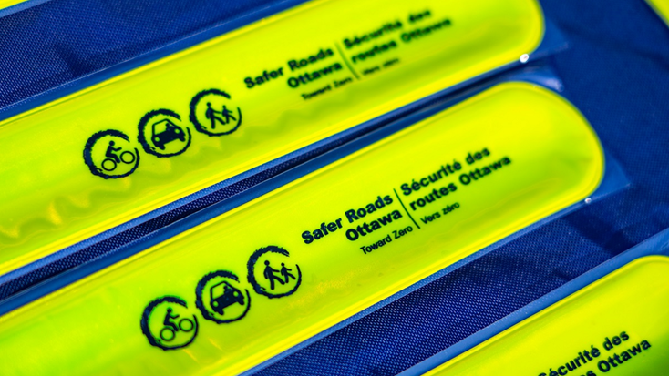 Close up view of yellow reflective bands with the logo of Safer Roads Ottawa: Towards Zero