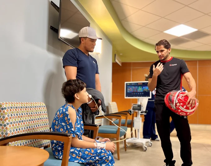 Pietro Fittipaldi standing up, speaking to man and child. Child is sitting down.