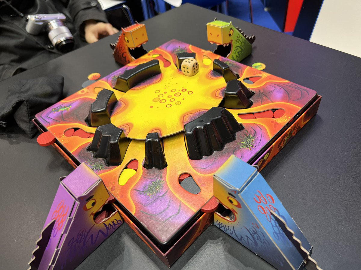 krstbg's tweet image. シュピール’23  1日目。「おいしい溶岩（Lecker Lava）」。ダイスの出目だけ穴から溶岩ディスクを差し込むと、押し出されたディスクが他の穴から落ちてくる。差し込む前に溶岩を食べれそうな穴にドラゴンを移動するのだけど押し出しは超ランダム。移動したら、さっきいた場所から落ちまくり！#SPIEL23