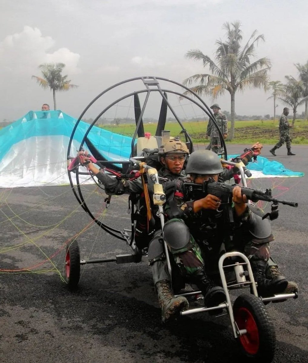 GerryS's tweet photo. Banyak yang kaget ketika melihat Paramotor digunakan sebagai Air Assault vehicle oleh Hamas dalam serangannya ke Israel.

Hal ini sebenernya bukan hal yang baru maupun unik. Setahu saya konsep ini sudah dicoba oleh beberapa militer di dunia, termasuk pihak TNI.
Lucunya, banyak yang bilang Paramotor Air Assault ini adalah hal yang bodoh, karena akan lebih efektif menggunakan helikopter, dan Paramotor akan jadi target empuk untuk aset-aset air defence modern, apalagi dengan rudal-rudal air defence, paramotor air assault itu akan menjadi suicide attack.

Eits, ntar dulu. Dalam combat doctrine, memang harus ada standard solutions untuk menjawab setiap tantangan, tetapi bukan berarti non-standard solutions itu haram atau bodoh.

Ironisnya, justru dalam penyerangan menuju target yang tergantung kepada rudal air defence ini, idealnya malah mungkin pakai paramotor air assault. Kenapa?

Helikopter itu radar signature dan heat signaturenya tinggi, jadi akan mudah terlihat oleh radar atau infra-red seeker. Mau bermain dengan ground clutter (main petak umpet menggunakan terrain, pepohonan ataupun bangunan memang bisa mengecohkan air defence systems, tapi kalau sudah dekat akan susah (dan harus menggunakan self-protection system seperti flares dan DIRCM). Heliborne assault menuju heavily defended target cukup beresiko dan mission planner harus memperhitungkan estimated lossesnya dari transit sampai assault landingnya dengan cermat.

Kalau Paramotor ini memang kelihatan konyol, tapi ideal untuk assault yang tidak membutuhkan jumlah pasukan yang banyak. Kenapa?

1. Murah, baik alat maupun trainingnya.

2. Pelan itu kadang malah jadi advantage. Kalaupun ketahuan oleh air defence radar, salah satu metode untuk homing oleh rudal radar guided adalah melihat object apa yang karakternya beda dari pantulan2 ground clutter, yaitu dengan melihat benda yang bergerak, ketika dalam terminal phase yang biasanya top-down. Makin pelan targetnya, makin susah membandingkannya dengan ground clutter.

3. Infra Red signature yang rendah. Untuk IR guided surface to air missile, identifikasi target dilakukan dengan mencari sumber panas yang bergerak. Mesin turbin itu enak buat IR guided missile, karena exhaustnya yang cukup panas dan semburan gas panasnya mengikuti si mesin/pesawat. Kalau mesin piston kecil seperti yang digunakan di Paramotor, heat signaturenya jauh dibawah mesin turbin jadi IR guided SAM bisa kesusahan untuk mendapatkan solution lock.

4. Mau main petak umpet menggunakan surrounding scenery lebih gampang karena kecepatannya yang pelan. Paramotor bisa menuju target dengan bermain diantara pohon dan bangunan dengan jauh lebih mudah dibanding helikopter. Suaranya yang mirip dengan kendaraan motor/mobil juga tidak akan membuat penjaga di target curiga.

Kelemahannya adalah, karena pelan dan tidak ada proteksi bagi yang ada di paramotornya, kalau sudah terihat secara visual, ditembakinnya gampang, tidak perlu pakai alat-alat air defence canggih, cukup senapan otomatis atau senapan mesin, untuk melumpuhkannya.

Antara land assault, helicopter air assault, atau paramotor air assault, mana yang ideal itu tergantung dengan profil target, defence assetsnya, dan threat assesmentnya.

Jadi jangan kaget. Makin canggih air defence sebuah target, kadang solusinya malah lucu-lucu. Apa aja itu?

Kita ambil contoh yang bukan rahasia aja yah. Ada gyrocopter:
1. Gyrocopter militer RRC.
2. Sapphire 3 Gyrocopter bikinan Ukraina juga pernah di tes untuk kebutuhan air reconnaissance dan air assault.
Dengan kompetisi pengadaan alutsista, kita sering dicekoki informasi barang-barang yang canggih dan mahal, sampai kadang kita lupa, bahwa low tech solutions bahkan solusi-solusi yang dianggap dagelan, tetap harus dijaga dan dikembangkan.