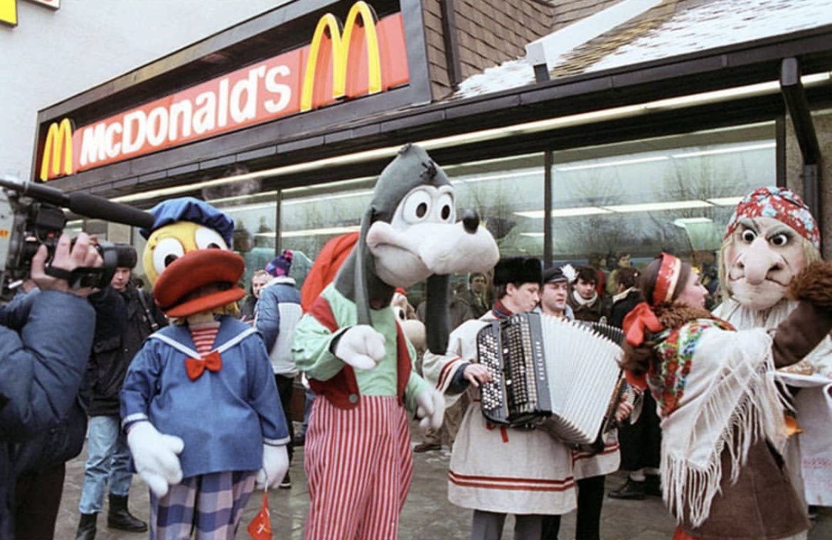 historyinmemes's tweet photo. The first McDonald's in the Soviet Union opened in Moscow on January 31, 1990. At the time of its construction, the Moscow McDonald's was the largest in the world with 900 seats, run by a staff of about 600 workers who were carefully selected from 35,000 applicants. A Big Mac was selling for 3.75 rubles (equivalent to $2.34 US dollars in 1990) in a country where the average salary was 150 rubles at the time. On opening day, 5,000 Soviet citizens lined up, and approximately 30,000 customers passed through the door that day.

The lines continued to grow well into the summer months as people from other cities flocked to McDonald's. One of them was photographer Mitya Kushelevich, who gave the following account:

"We stood under the melting sun for around eight hours. That wasn't so much of a problem as we were used to standing in lines for days just to get our monthly ration of sugar and tea. Once inside, we were blown away by the number of young cashiers behind the huge counter, smiling, moving like bees, serving one meal after another. Nothing like our fat old ladies in white gowns sitting in front of empty shelves, pyramids of dusty canned food as window dressing. I still remember how insanely huge the milkshake looked, and I didn't know how to hold a Big Mac with my tiny hands.

Everything tasted more intense than anything I'd ever tried before. I ate and drank and chewed like it was my last meal on earth. Around ten minutes and 5,000 calories later, my body alerted me to the fact that it wasn't quite able to digest all the fatty deliciousness and that it was probably a good time to check out how an American toilet looked like from the inside. I wasn't alone: the queues to the toilets, especially the women's, were almost as long as the queues outside."