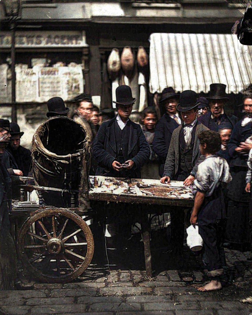 englandincolour's tweet photo. Costermonger Joseph Carney sells fresh herring from his barrow in the street market between Seven Dials and Five Dials in London, 1877. #victorians #fishmarket #costermonger #streetmarket #market #sevendials #fivedials https://t.co/u03gAApCWR