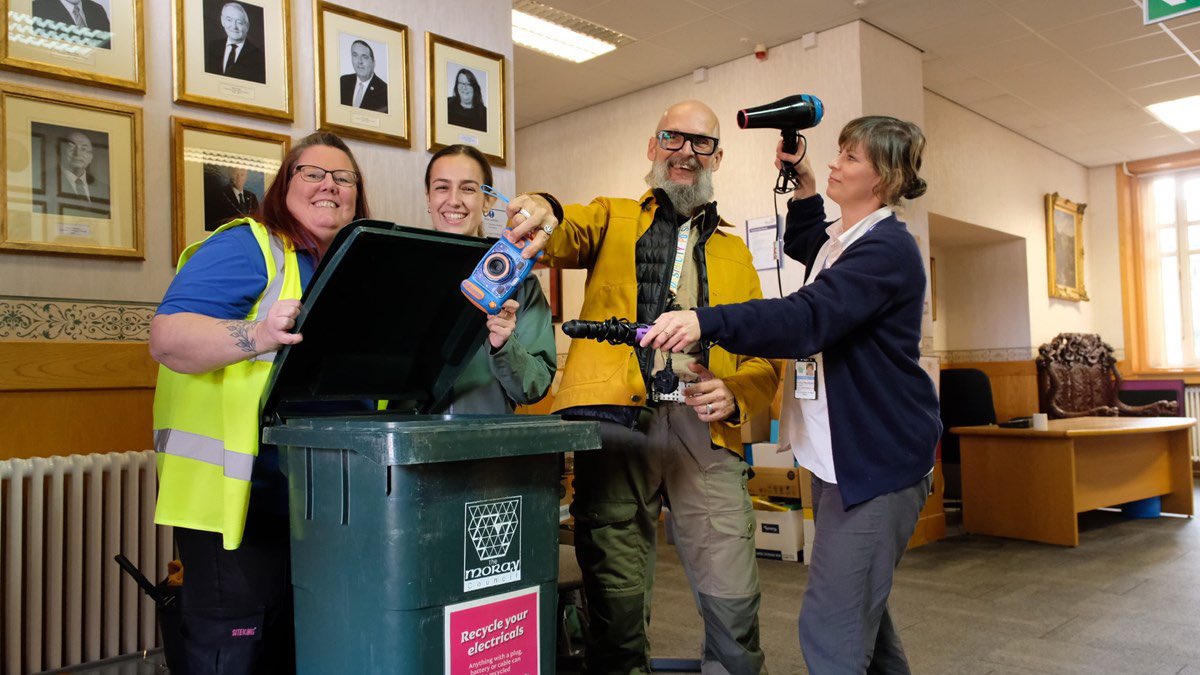 draeyk's tweet image. Council officers clown around with Moray's Climate Change Champion, Cllr Draeyk Van Der Horn, as they put their broken and old electricals into one of the new staff e-waste recycling bins. #recyleweek @MorayGreens @scottishgreens