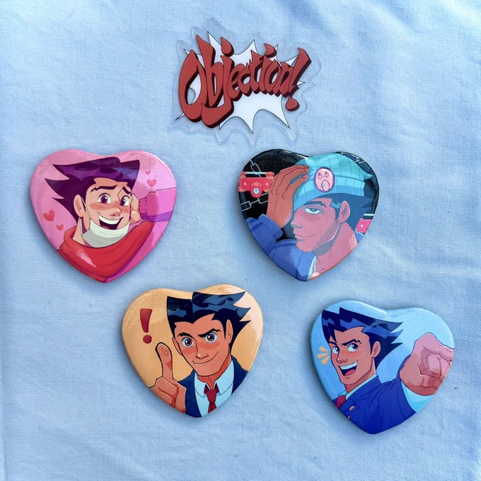 PRE-ORDERS UPDATE The good omens gummies and phoenix heart buttons arrived today and I'm SO happy with them!! Looking forward to mailing these out ASAP! Ace attorney gummies sticker sheet is still in production 
