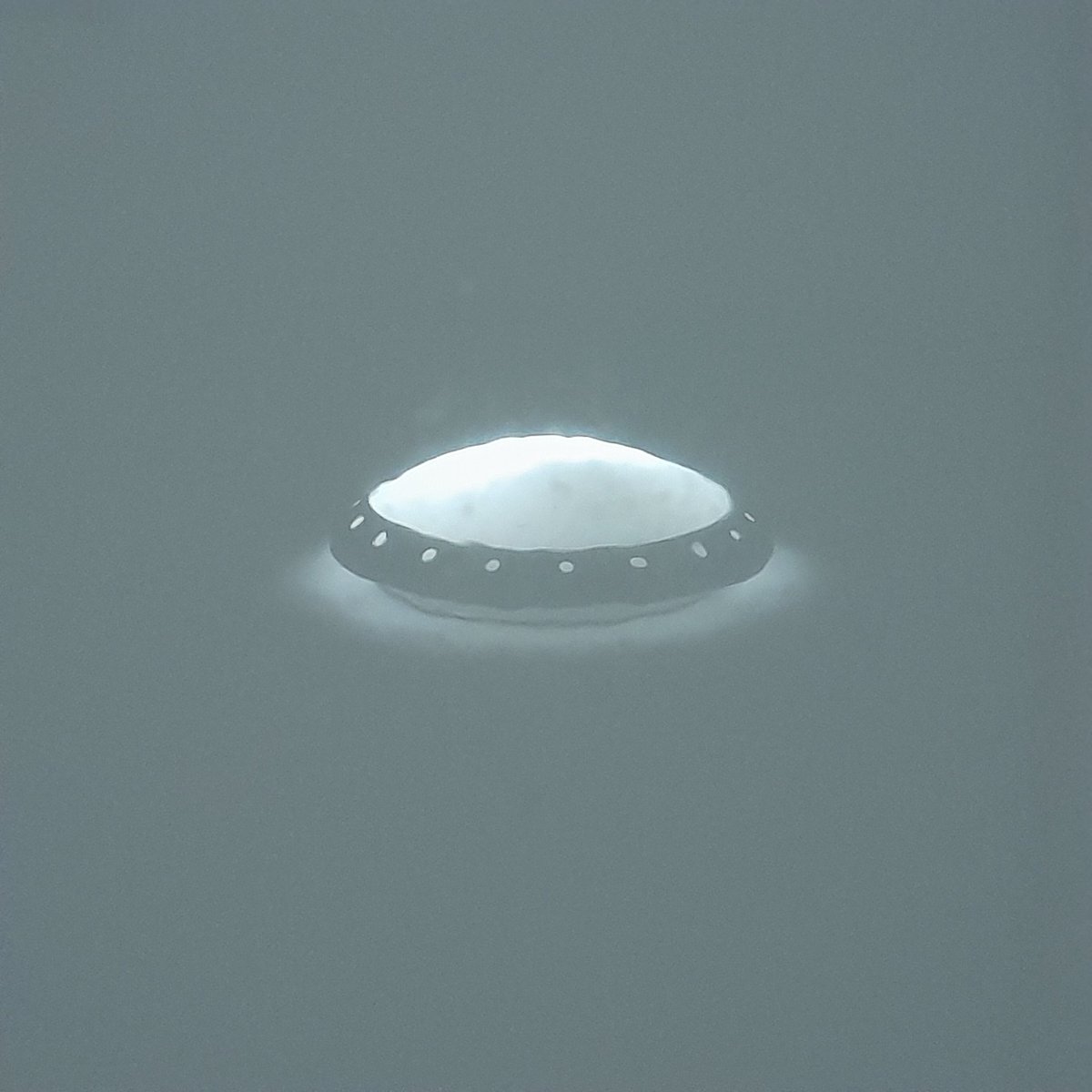 The reflection (turned upside down) of our bathroom light on one of our shower tiles looks like a UFO.