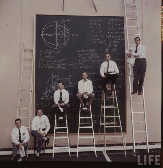 Scientists using ladders and chalkboard to work out equations for satellites in orbit, ca. 1957.