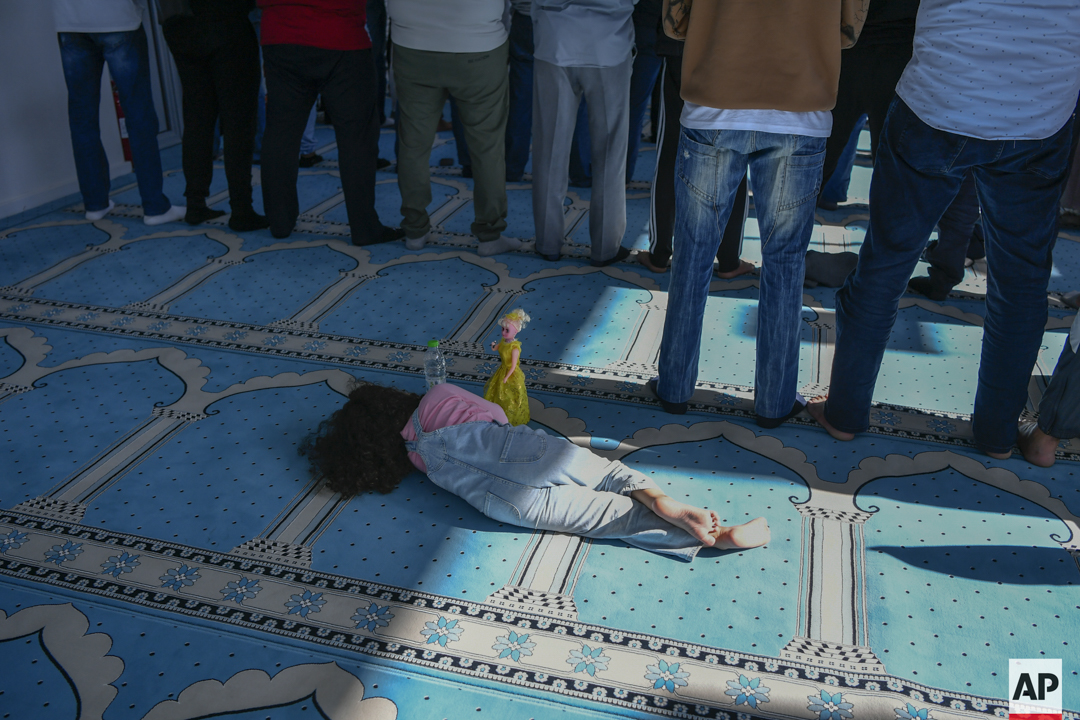 michaelvaraklas's tweet image. A girl lies on the floor as men pray in a mosque in Athens, Greece, Friday, Oct. 13, 2023.  (@AP_Images/ @michaelvaraklas )