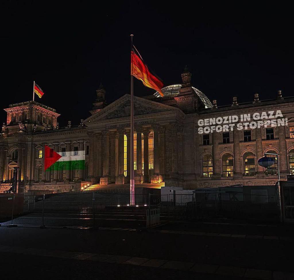 OnlinePalEng's tweet photo. Activists light up the Palestinian flag with the phrase “Stop Genocide in Gaza” on the German Parliament building. https://t.co/nis58bwZkJ