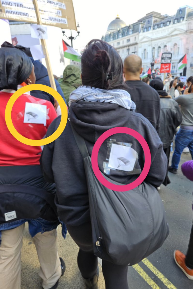 These are pro-Hamas protestors in London. The stickers on their back are of the Hamas paragliders, who who initiated the massacre in Israel. They may as well have ISIS stickers or Swastikas. Churchill is rolling in his grave now!