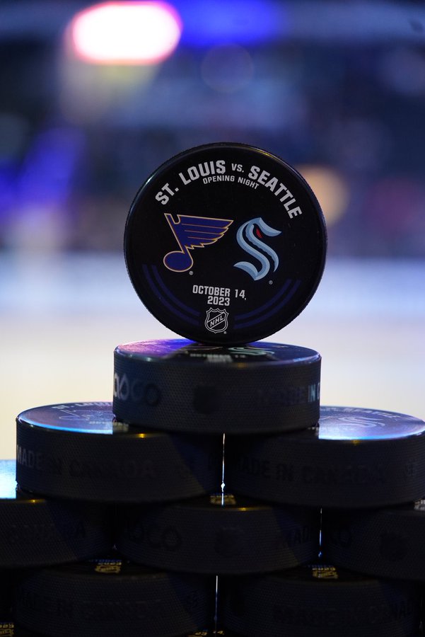 Photo of a puck with the blues and kraken logos on it. the details of tonight’s game are written in white block letters