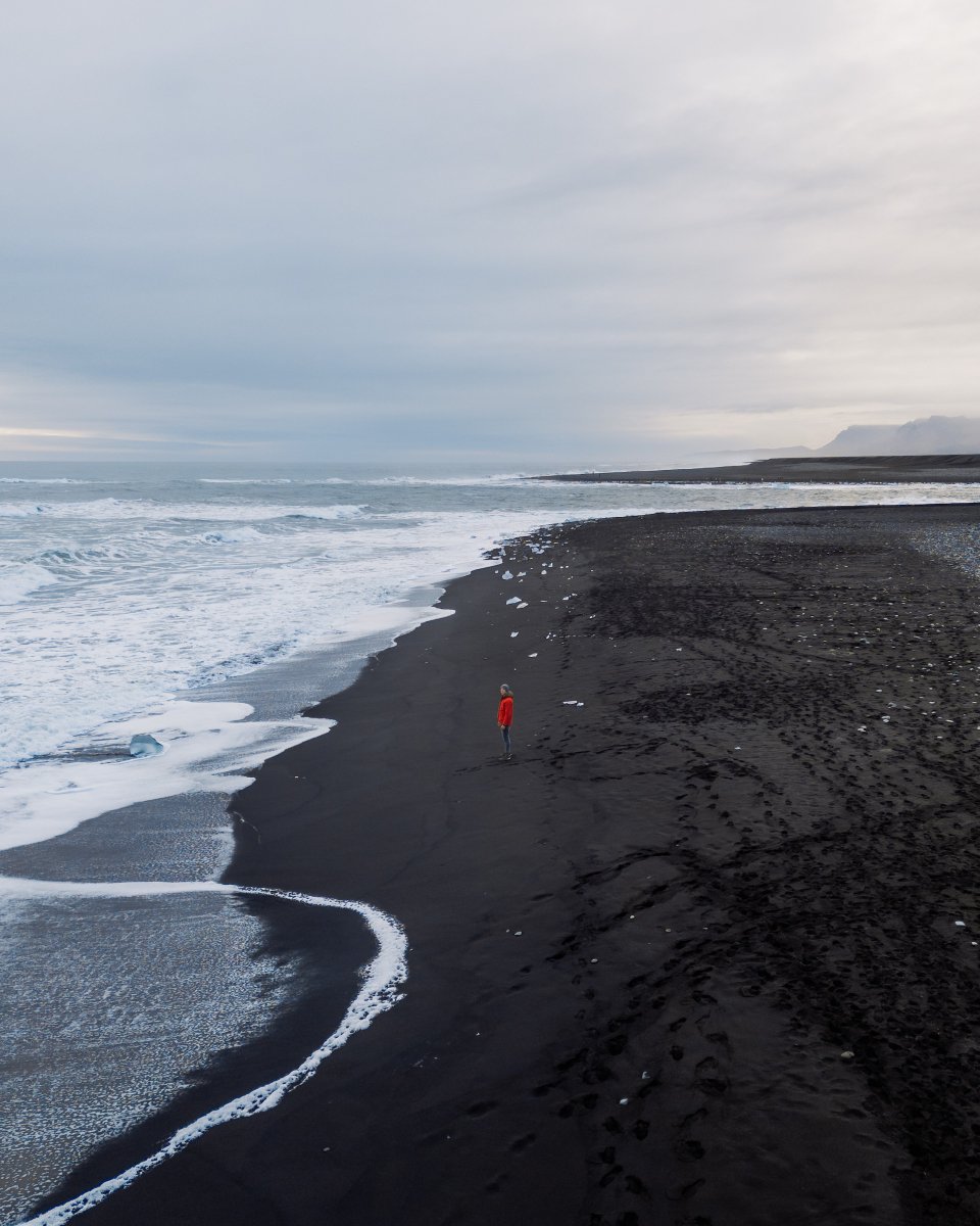 Finding solitude on Iceland's vast black sand shores. 🌊 The dance of frothy waves, the embrace of the cool breeze, and that endless horizon.
