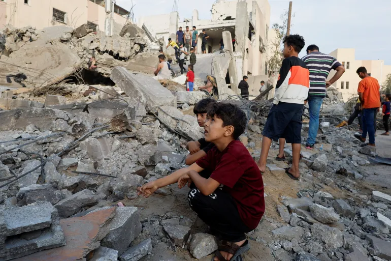 TanjidSaim's tweet photo. Israel’s order for 1.1 million people in northern #Gaza to move south could amount to a forcible transfer of civilians.
Palestinian children sit amid the rubble as others inspect a building destroyed in #Israeli raids in Khan Younis in the southern Gaza Strip 
#FreePalestine https://t.co/qdf2v7SbIZ