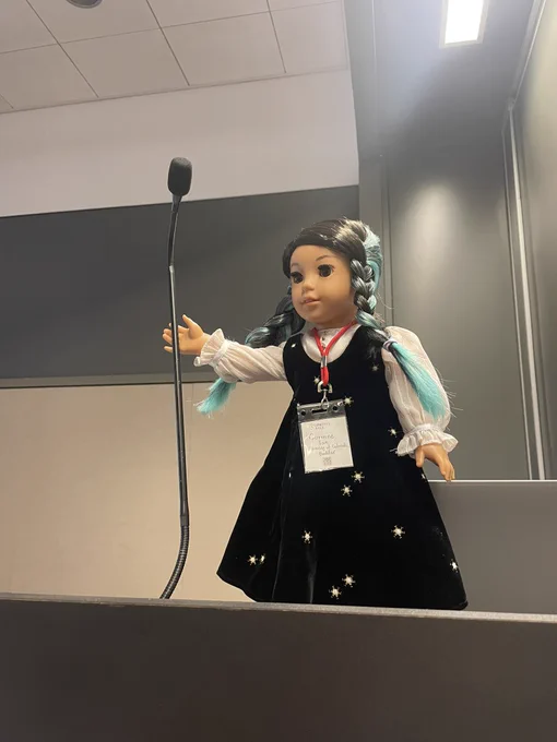 Corinne on the podium holding a mic