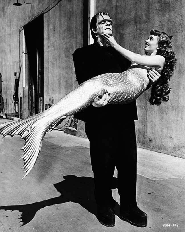 artribune's tweet photo. #fotodelgiorno: Una giornata qualunque neglli Universal studios nel 1948. In questa immagine l'attrice Ann Blyth, indossa una pinna da sirena da 20.000 dollari per un film e non può camminare. Per questo Frankenstein Glenn Strange è venuto dal set vicino per dare una mano. https://t.co/t1ptZLOOwN