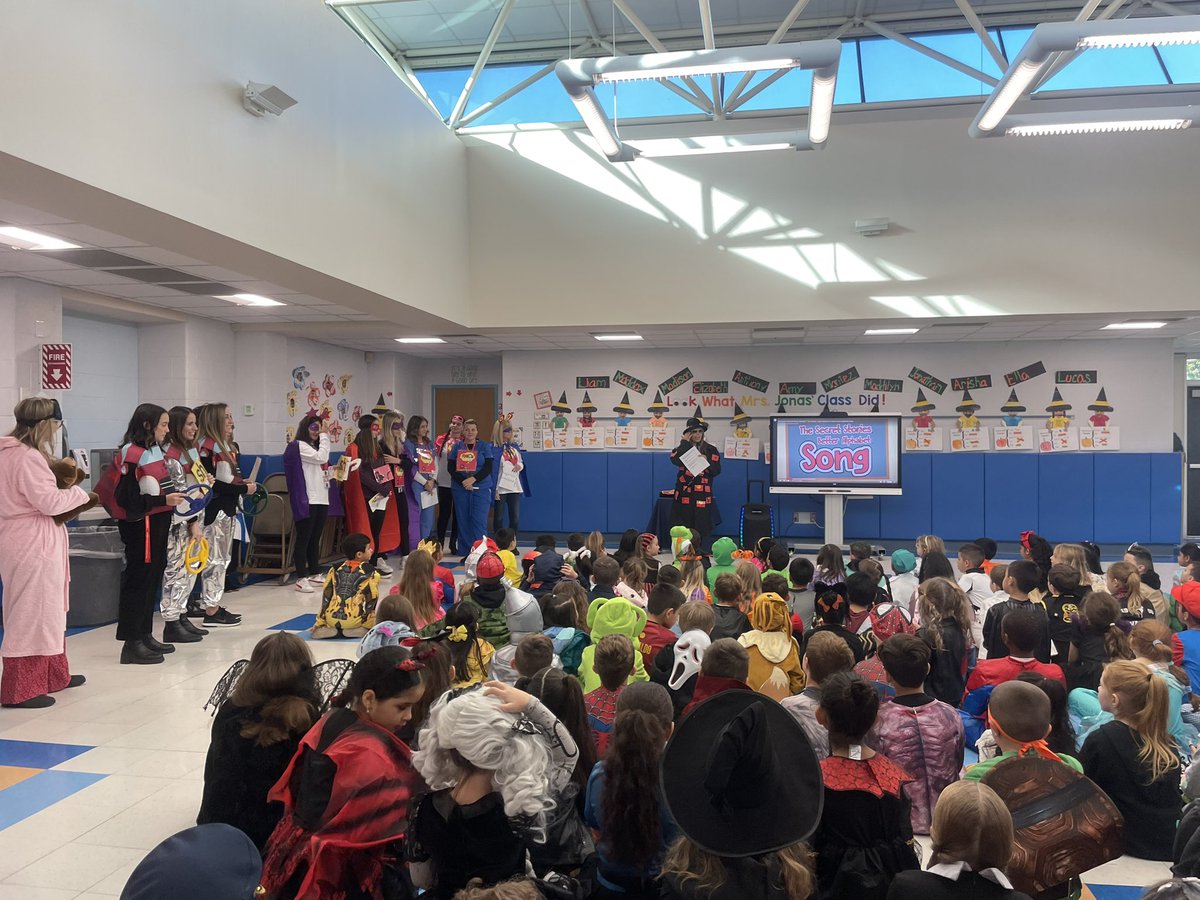 SlocumCSD's tweet photo. Mrs. Dluginski kicked off Halloween with a K-2 assembly about the Secret Stories! She had a little help from Slocum faculty and staff. Grades K-2 finished the assembly by singing The Secret Stories Better Alphabet Song that they have all been practicing in class! #SlocumShines https://t.co/sy1FClGLRm