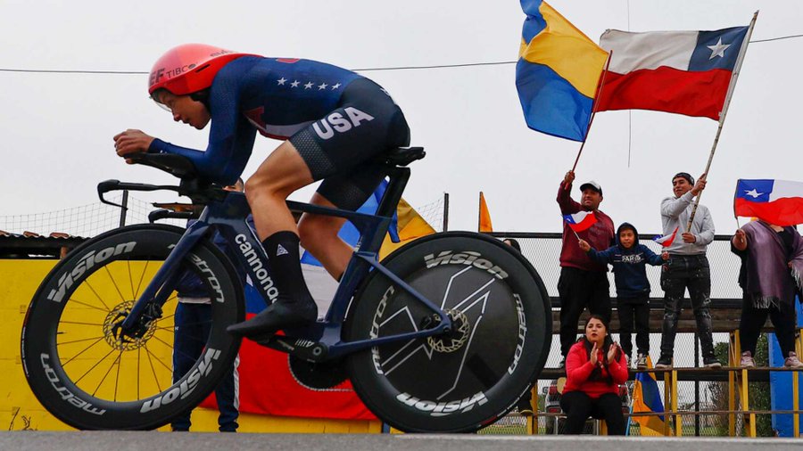 Faulkner en acción sobre su bicicleta y el público moviendo banderas de fondo