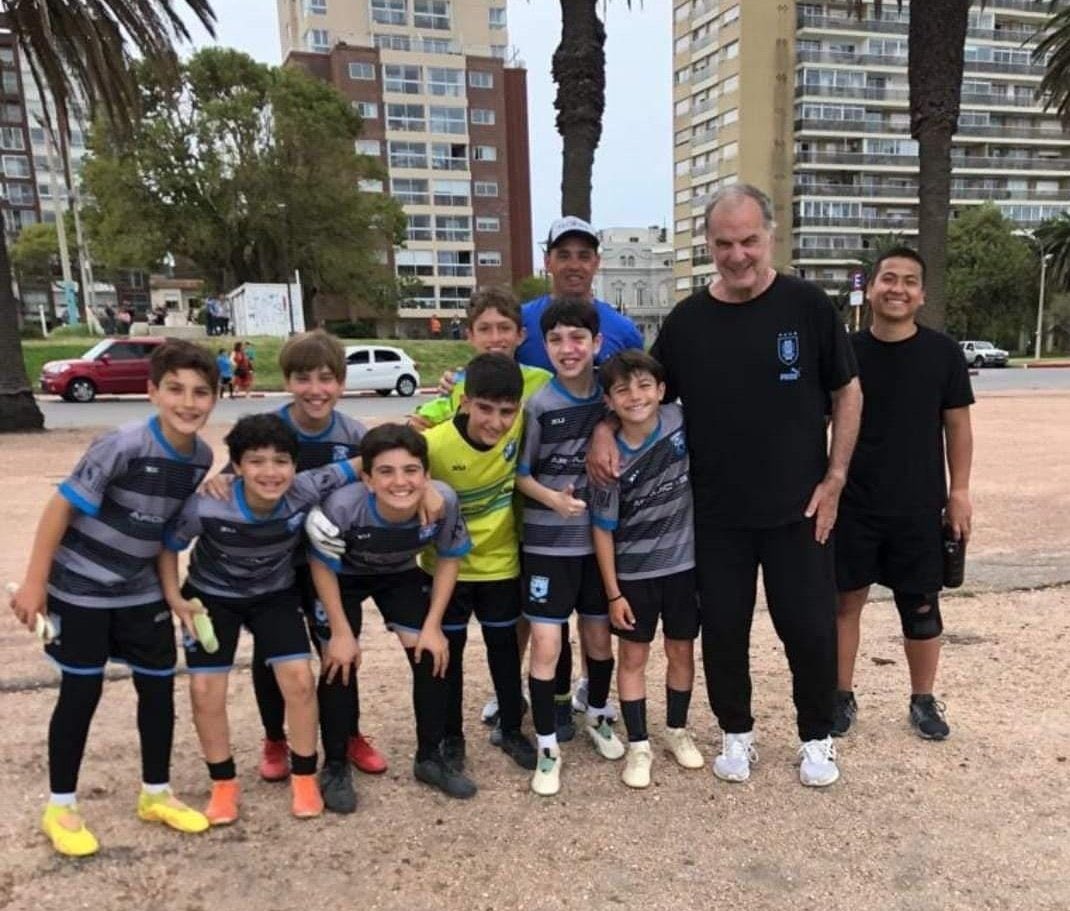 Newells_en's tweet image. Marcelo Bielsa and the young players of the Estrella del Sur club who he met while out on his walk around Montevideo.