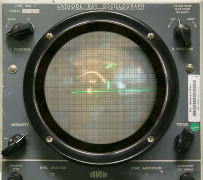 A DuMont Lab Oscilloscope Type 304-A projecting a match from "Tennis for Two." The grey-green instrument is in the shape of a box with a circular screen in the center and black knobs in all four corners. The screen shows a grid that has a neon green line on the horizon and a small vertical line to simulate the tennis net.