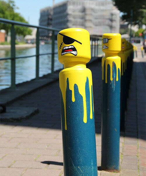 Le CyKlop, a street artist in France converts city bollards into LEGO-inspired caricatures using yellow spray paint and his own sticker designs, while everyone is asleep!