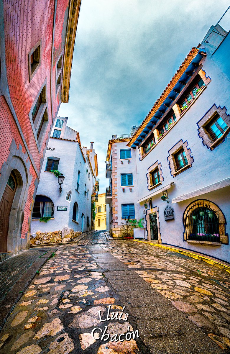 RetallsdeSitges's tweet photo. Als carrers empedrats de Sitges, un raconet on el temps es fon. Edificis de corbes dalinianes, colors dansaires com notes musicals. L'eternitat es revela a cada adoquí. Has explorat aquesta poesia d'art i temps? 💫🏛️🎨 #Sitges #RetallsdeSitges #LluisChaconphoto https://t.co/2NhHlHyWYl